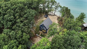 A secluded cabin with a deck and a covered area, surrounded by dense forest and overlooking a body of water. - 🐻 Beautiful Overlooking Shoreline 2bdr Chalet 18396 (Arcadia)