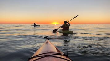 A kayak on calm water with a sunset in the background.
