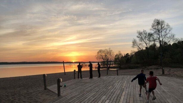 A wooden boardwalk leading to a beach with a sunset in the background.