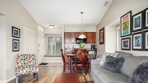 A modern living room with a grey sofa, wooden coffee table, and a dining area with a wooden table and chairs.