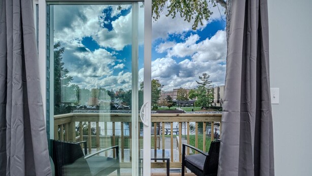 A balcony with a glass door, a chair, and a table. - The Riverwalk Retreat on the Fox - Waterfront Vacation Rental in Downtown Mchenry 3br/2ba Home With Private Pier (McHenry)