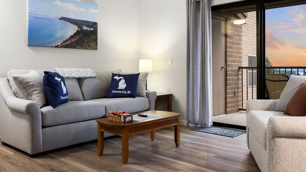 A living room with a grey sofa, a wooden coffee table, and a painting of a coastal landscape. - Newly Updated Lakeview Golf Retreat 1bdr Condo Resort 5057 (Williamsburg)