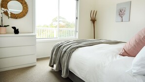 A bedroom with a bed, a dresser, a mirror, a window, and a potted plant. - Coastal Haven, 5 minute walk to beach. (Flinders)