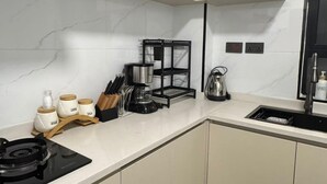 A compact kitchen with a stove, sink, and a coffee maker on the counter. - 1 bedroom kilimani centrally located (Nairobi)