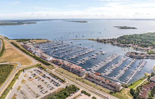 A marina with numerous boats docked, surrounded by residential buildings and a large parking area. - Beach front ship in Ouddorp with house sea view (Ouddorp)