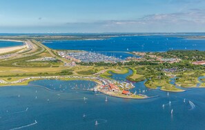 An aerial view of a coastal marina with numerous boats, a large parking area, and surrounding greenery. - Beach front ship in Ouddorp with house sea view (Ouddorp)