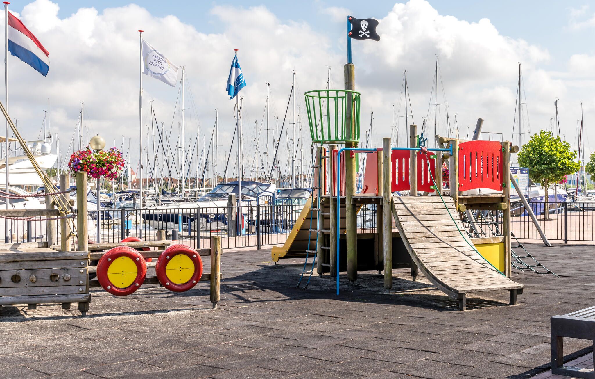 A playground with a slide, climbing net, and a pirate flag.
