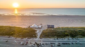 An aerial view of a coastal area with a parking lot, buildings, and a beach.
