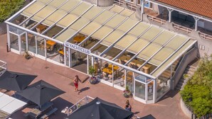 A glass-enclosed building with outdoor seating, labeled "YACHTCLUB".