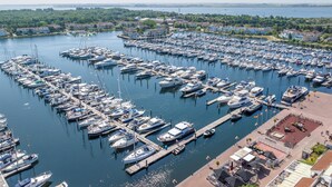 An aerial view of a marina with numerous boats docked, surrounded by residential buildings and greenery.
