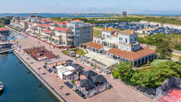 A coastal hotel with multiple buildings, a marina, and a parking lot.