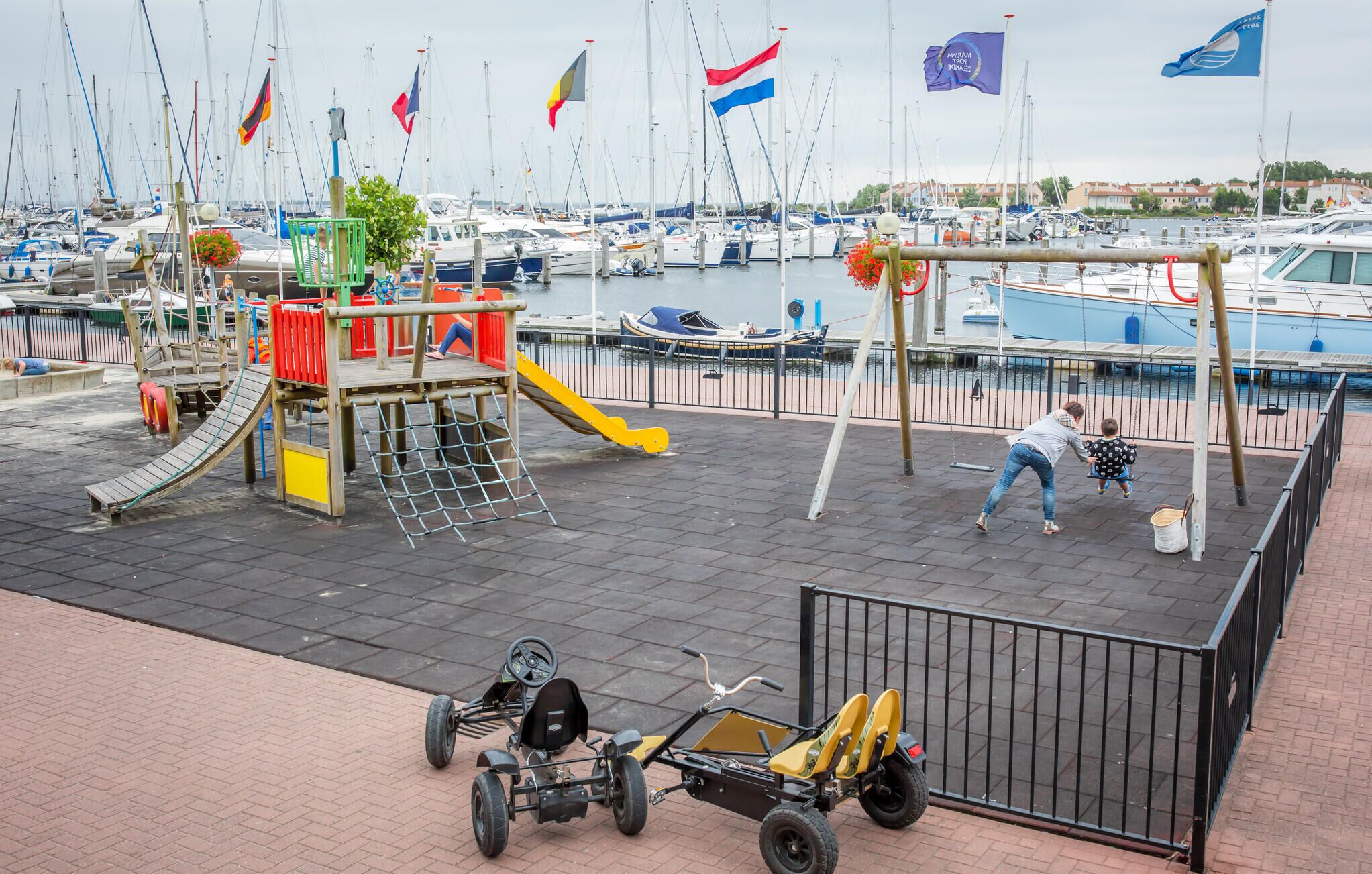 A marina with boats, a playground, and a paved area with a go-kart.