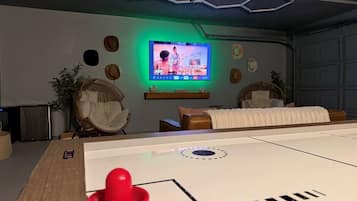 Ein Zimmer mit Kicker, Fernseher und einer Sitzecke mit Sofa und Sesseln.