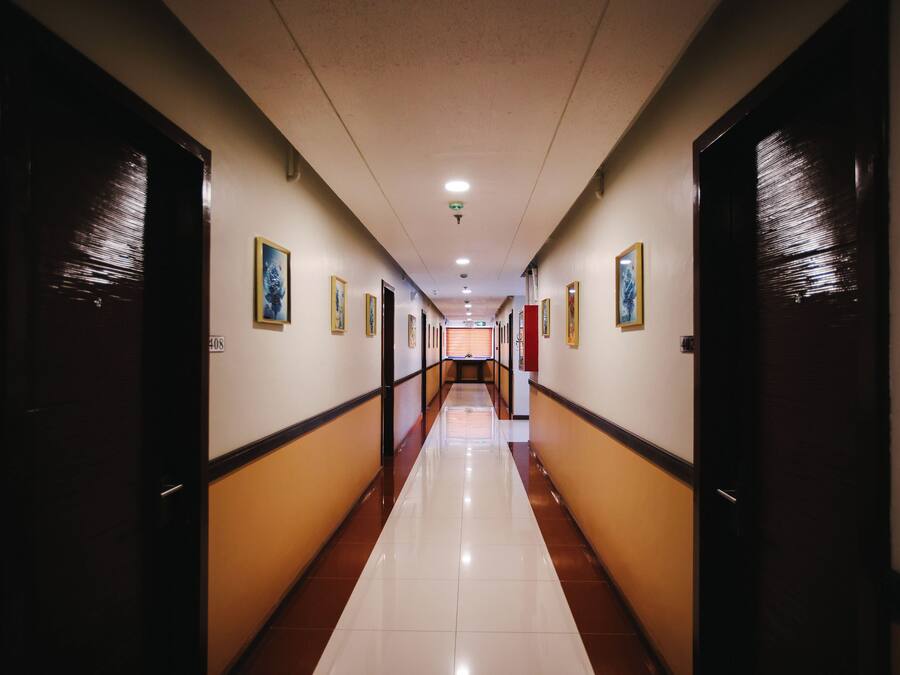 Passadís llarg i estret d'un hotel, amb portes a banda i banda, sòl de rajola i quadres penjats a les parets.