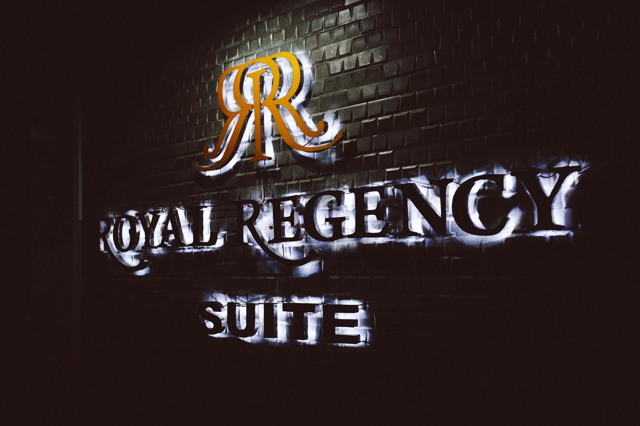 Une enseigne portant l’inscription « ROYAL REGENCY SUITE » et un logo stylisé en forme de « R ».