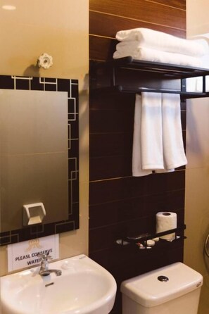 A bathroom with a sink, toilet, and towel rack. A sign on the wall reads "Please conserve water." - Surigao Royal Regency Suites (Surigao)