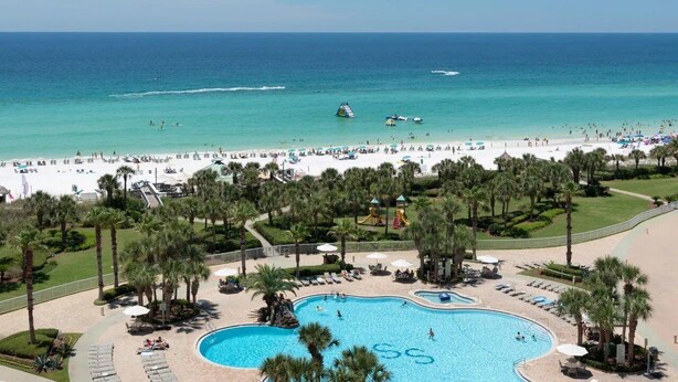 Un resort con una grande piscina, spiaggia e palme.