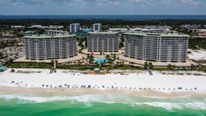 Un complesso alberghiero sulla spiaggia con diversi edifici circolari, una spiaggia sabbiosa e una vista limpida sull'oceano.