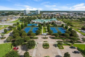 Vue aérienne d’un hôtel doté de plusieurs courts de tennis, d’un parking et entouré de verdure.