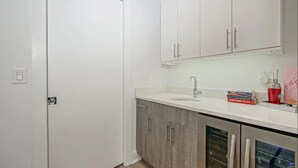 Un bagno moderno con una porta bianca, mobili in legno, un lavandino e un piano di appoggio con articoli da toilette.