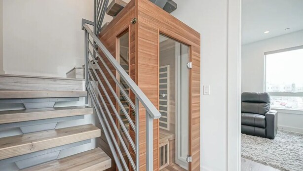 Una moderna scala con gradini in legno e ringhiere in metallo, che conduce a una stanza con una porta in vetro e vista sulla città.