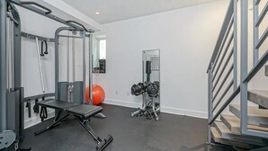 Una palestra in casa con una sbarra per trazioni, una panca per pesi, manubri e uno specchio.