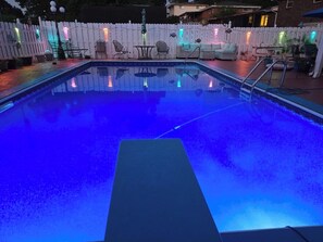 Ein Schwimmbad mit weißem Zaun und Gartenmöbeln.
