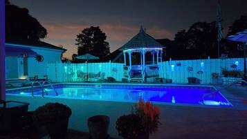 Una piscina con un gazebo e un recinto di legno bianco.