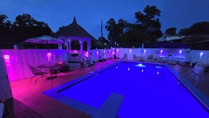 Uma área de piscina com um gazebo, espreguiçadeiras e uma cerca.