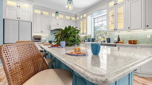A modern kitchen with white cabinets, a large island, and pendant lighting. - Harbor View Retreat with Heated Pool, Wraparound Decks & Sunset Vibes - Sunset Harbor - Roelens (Punta Gorda)