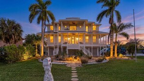 A two-story house with a front porch, palm trees, and a mailbox. - Harbor View Retreat with Heated Pool, Wraparound Decks & Sunset Vibes - Sunset Harbor - Roelens (Punta Gorda)
