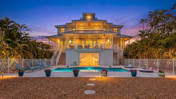 A multi-story house with a swimming pool, outdoor seating, and a well-lit entrance. - Harbor View Retreat with Heated Pool, Wraparound Decks & Sunset Vibes - Sunset Harbor - Roelens (Punta Gorda)