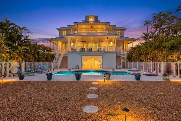 Une maison à plusieurs étages dotée d’une piscine, d’un espace extérieur aménagé et d’une entrée bien éclairée.