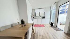 A modern kitchen with white cabinets, a wooden dining table, and a small Christmas tree. - Espinho Beach House by Trip2Portugal (Espinho)