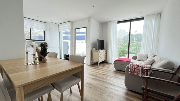 A modern living room with a wooden dining table, a sofa, and a TV on a cabinet. - Espinho Beach House by Trip2Portugal (Espinho)