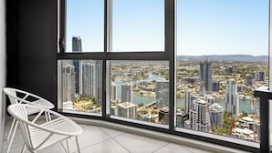 A balcony with a city view, white chairs, and a large window. - Level 42 Beachside 1BR Apartment with Ocean Views (Surfers Paradise)