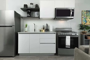 A modern kitchen with stainless steel appliances, white cabinetry, and a microwave above the stove. - Apartment Lower Level in Casco View (Panama City)