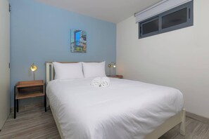 A bedroom with a bed, two bedside tables, a nightstand, a window, and a wall-mounted artwork. - Apartment Lower Level in Casco View (Panama City)