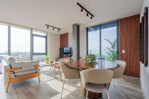 A modern living room with a dining area, large windows, and a city view. - Apartment Upper Level in Casco View (Panamá)