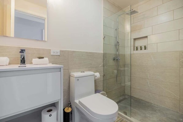 Ein modernes Badezimmer mit Toilette, Waschbecken und Duschbereich.