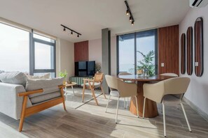 A modern living room with a sofa, dining table, chairs, and a TV. - Apartment Upper Level in Casco View (Panamá)