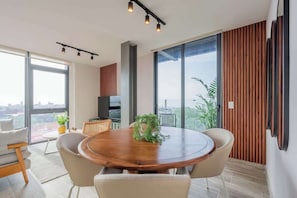 Ein stilvoller Essbereich mit einem runden Holztisch, vier Stühlen und einem großen Fenster mit Blick auf die Stadt.