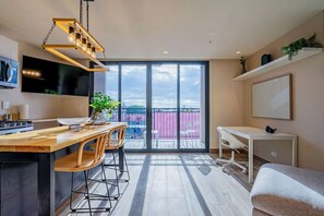 A modern kitchen with a wooden countertop, bar stools, and a hanging light fixture. - Apartment Lower Level in Casco View (Panamá)