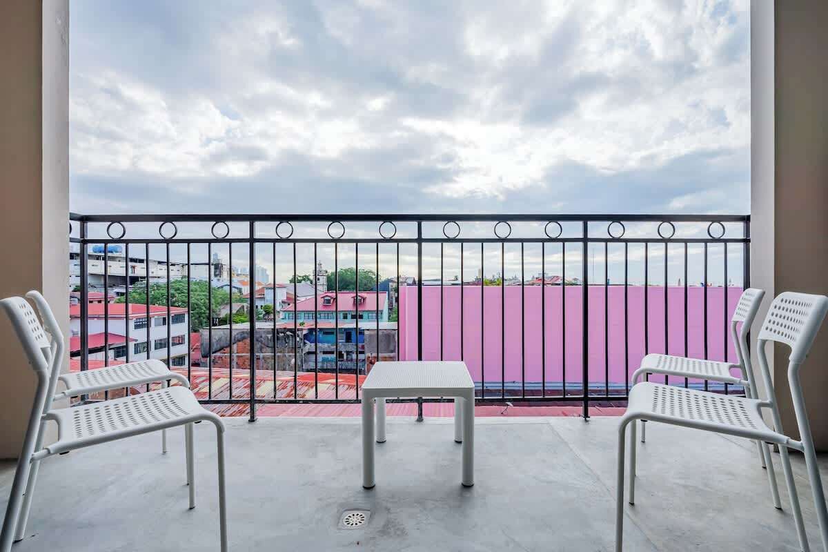 A balcony with a metal railing, two white chairs, and a small table.