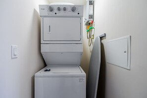 A front-loading washer and dryer unit with control knobs and a power outlet on the wall. - Apartment Lower Level in Casco View (Panamá)