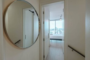 A hallway with a large mirror, a door leading to a balcony with a city view, and a ceiling fan. - Penthouse con piscina y vistas en Centro Histórico (Panamá)