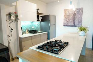 A modern kitchen with a gas stove, a refrigerator, and a coffee maker. - Penthouse con piscina y vistas en Centro Histórico (Panamá)