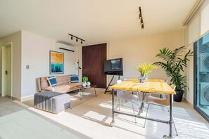 Ein modernes Wohnzimmer mit Sofa, Couchtisch, Esstisch und Fernseher.