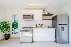 Een moderne keuken met witte kasten, een roestvrijstalen koelkast, een magnetron en een gasfornuis.