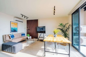 A modern living room with a sofa, a coffee table, a TV, and a dining table. - Modern Apartment in the Historic District (Panamá)